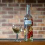 A Baron de Ley wine bottle and glass on a wooden table with a brick wall background.