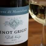 Close-up of Italian Pinot Grigio wine bottle and glass with reflections and blurred background.