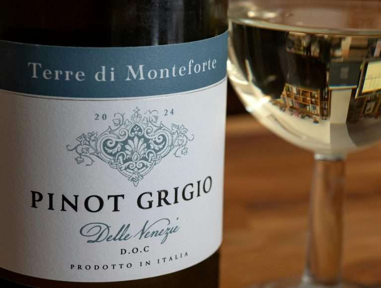 Close-up of Italian Pinot Grigio wine bottle and glass with reflections and blurred background.