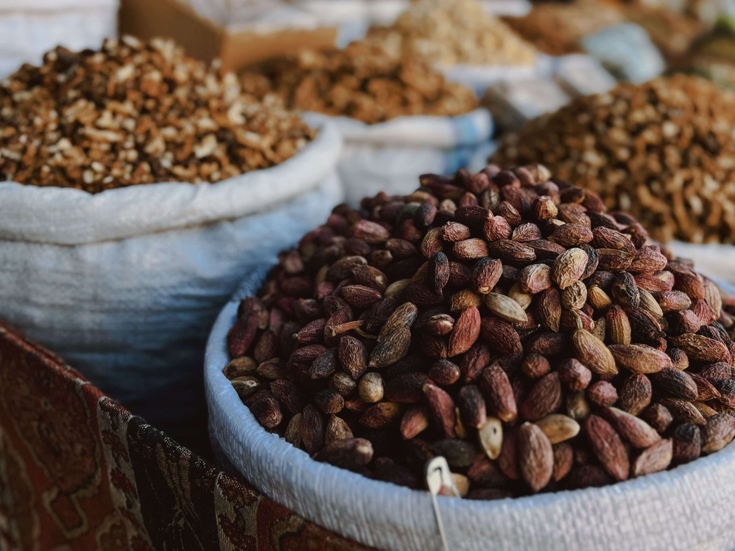 Close-up of assorted nuts in sacks at an outdoor market, showcasing textures and variety.